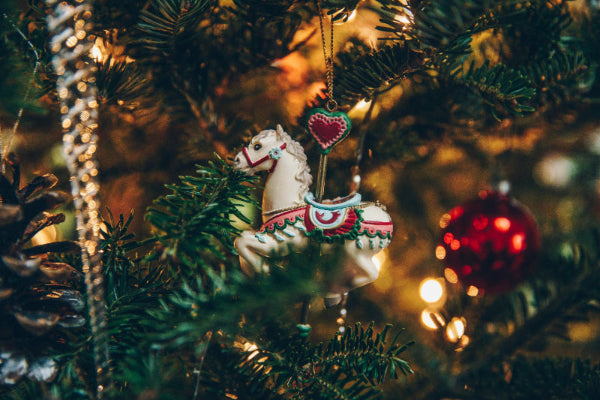 Decorative unicorn ornament on a Christmas tree with blurred lights in the background